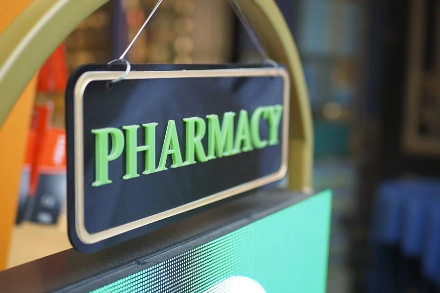 A pharmacy sign with green lettering and black background.